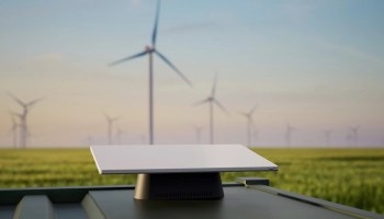 A Project Kuiper satellite terminal is set up with a wind farm in the background. (Amazon Photo)